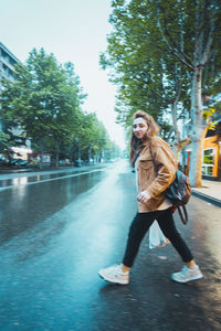 Portrait of smiling young woman standing on road against trees