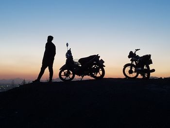 Silhouette people riding motorcycle against sky during sunset