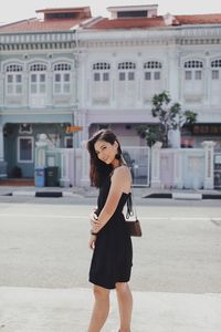 Full length portrait of young woman standing on road