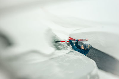 7 years old boy removing snow off a car during a snow storm