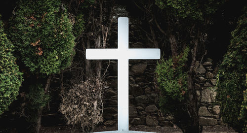 Low angle view of cross amidst trees in forest