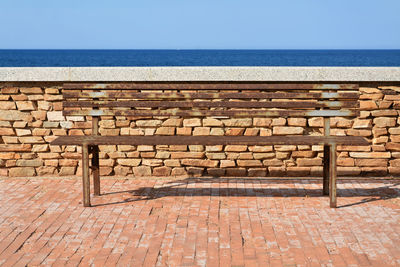 Brick wall by sea against clear sky