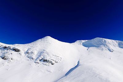 Scenic view of snowcapped mountains against clear blue sky