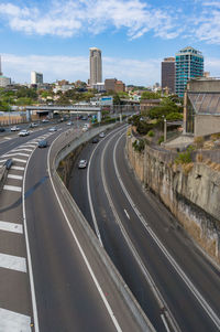 Road by buildings in city against sky