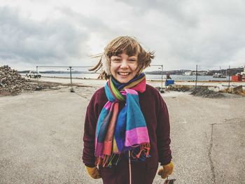 Portrait of smiling woman standing at beach against sky