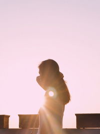 Side view of young woman standing against clear sky