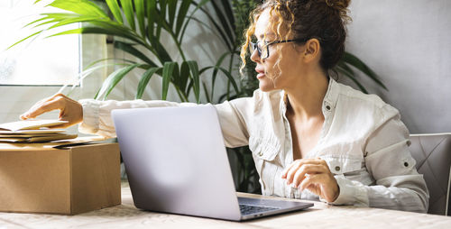 Young woman using laptop while sitting on table