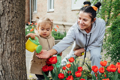 Spring gardening. senior woman grandmother and little toddler girl granddaughter watering tulips