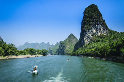 Scenic view of sea and mountains against clear blue sky