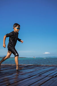 Full length of man standing in sea against clear blue sky