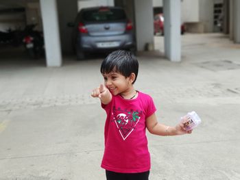 Smiling girl pointing while standing on footpath