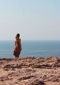 Woman standing at beach against sky