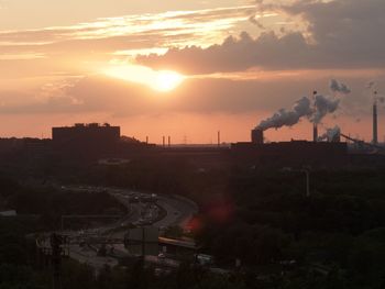 Smoke emitting from factory against sky during sunset