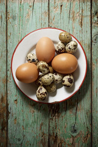 Quail and chicken eggs on a wooden table.