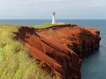 Lighthouse by sea against sky