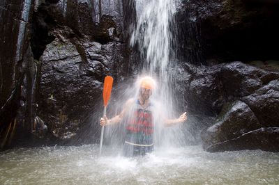 Man smiling under waterfall