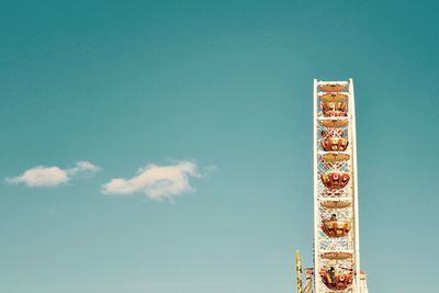 Low angle view of amusement park against blue sky