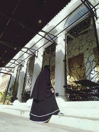 Rear view of woman walking against building