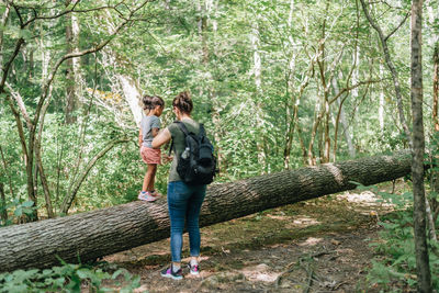 Full length of mother and daughter walking in forest