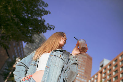 Woman holding disposable cup in city