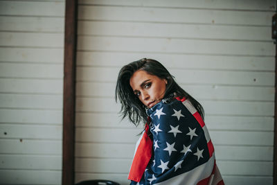 Woman with american flag against wall