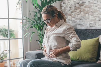 Young woman using laptop while sitting on sofa at home