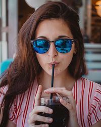 Portrait of woman drinking from straw