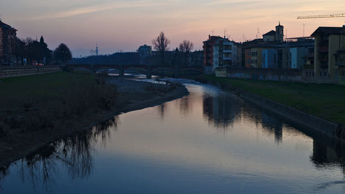 River amidst buildings against sky during sunset