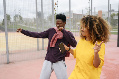 Young woman dancing with friend at sports field