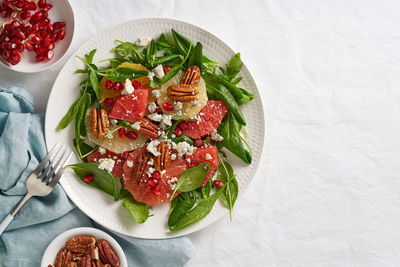 Top view fruits citrus salad with nuts, green lettuce leaves. balanced food. spinach 