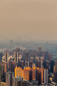 Buildings in city against sky during foggy weather