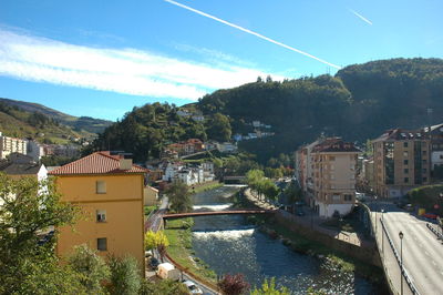 Buildings by river against sky in town