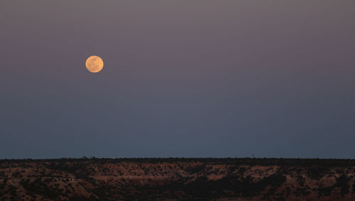 Full moon over landscape at dusk