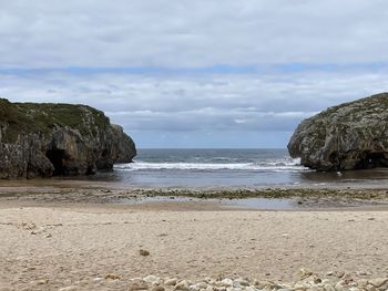 Rock formation on beach against sky