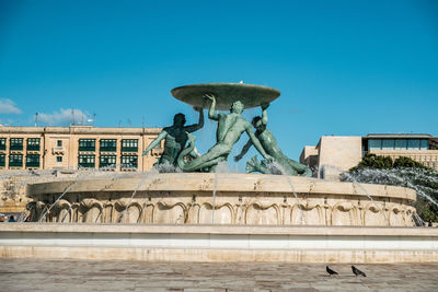 Statue in front of building against blue sky