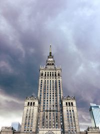 Low angle view of skyscrapers against cloudy sky