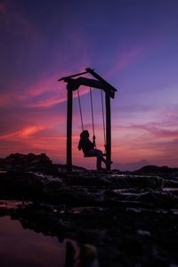 Low angle view of electricity pylon against sky during sunset