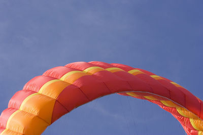 Low angle view of colorful parachute against blue sky
