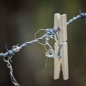 Close-up of barbed wire tied to metal fence