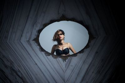 Portrait of young woman wearing bra while reflecting on mirror