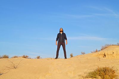 Full length of man standing on sand dune at desert against sky