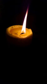 Close-up of lit candle against black background