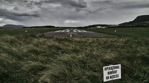 Information sign on field against sky