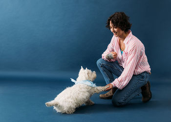 Side view of young man with dog against white background