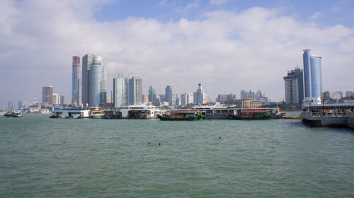 Sea by modern buildings against sky in city