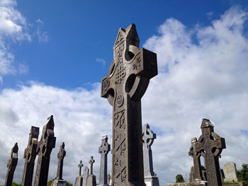 Low angle view of old crosses at cemetery against sky