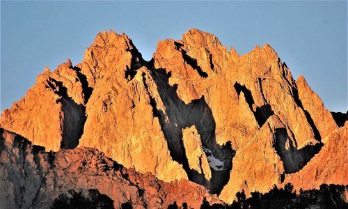 Low angle view of rocks on mountain against clear sky