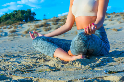 Low section of woman sitting on beach