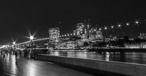 Illuminated bridge over river against sky at night