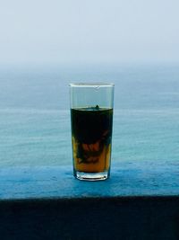 Close-up of beer on table against sea